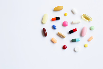 Colorful tablets with capsules and pills on white.