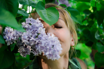 Fototapeta premium Middle age blond woman in lilac. Portrait of a woman in a flowered garden. woman in summer