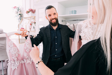 Luxury women clothing store. Fashion consultant presenting designer evening gown to female client.