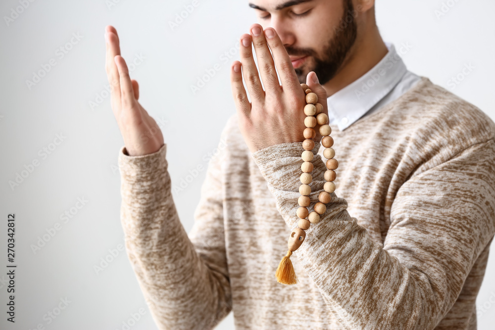 Wall mural young muslim man praying against light background