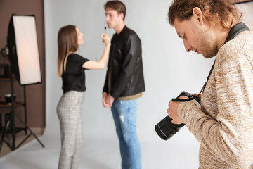 Photographer, makeup artist and model in modern studio
