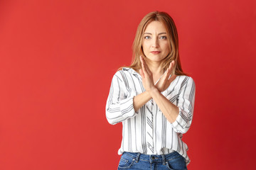 Portrait of mature woman rejecting something on color background