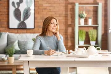 Portrait of mature woman writing in notebook at home