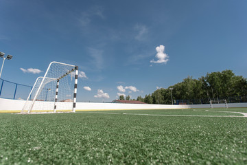 Football field. Artificial surface, green grass. Sport outdoors. Goal nets, white lines, circle...