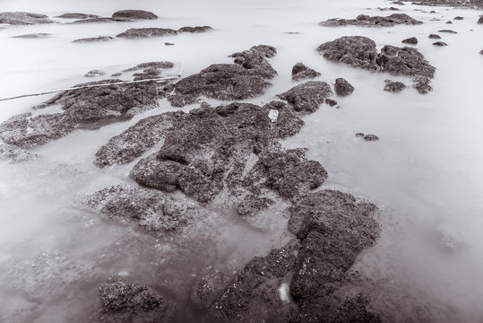Photo Black and White of Long Exposure Photography Waves on stone beach waters edge abstract sea background.Thailand.