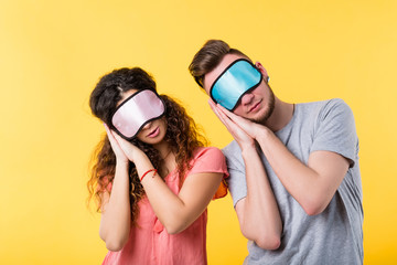 Bedtime concept. Healthy lifestyle and sleep habits. Tired young couple in homewear and eye masks going to have a rest.