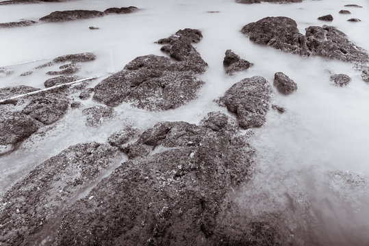 Photo Black and White of Long Exposure Photography Waves on stone beach waters edge abstract sea background.Thailand.