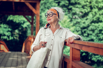 Bewitching aging lady leaning on the bridge outdoors