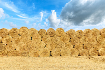 Straw bales on farmland with blue cloudy sky