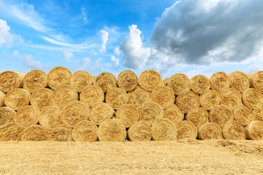 Straw bales on farmland with blue cloudy sky