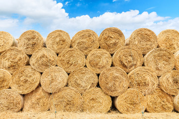 Straw bales on farmland with blue cloudy sky