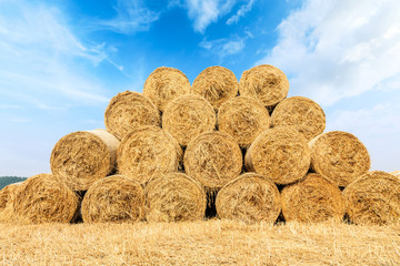 Straw bales on farmland with blue cloudy sky