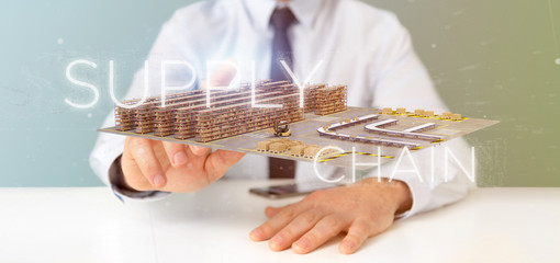 Fototapeta premium Businessman holding a Supply Chain title with a warehouse on background 3d rendering