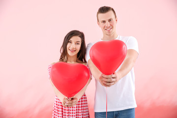Fototapeta na wymiar Happy young couple with air balloons on color background