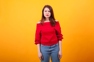 Portrait of beautiful young woman looking annoyed at the camera over yellow background