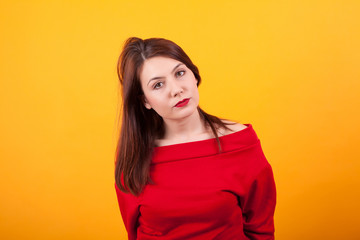 Portrait of gorgeous young woman looking serious at the camera over yellow background