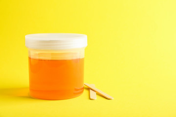 Container with sugaring paste for epilation on color background
