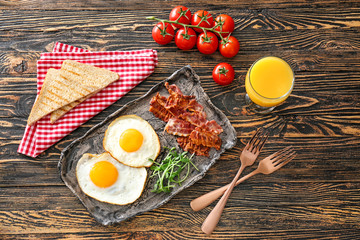 Composition with tasty eggs, bacon and toasts on wooden background