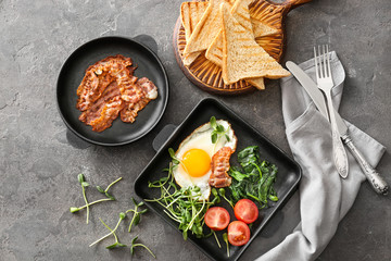 Composition with tasty fried egg and bacon on grey background