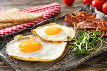 Plate with tasty fried eggs and bacon on table, closeup