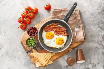 Traditional English breakfast with fried eggs, bacon, beans and toasts on table
