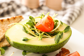 Tasty avocado with tomato and sprouts on plate, closeup