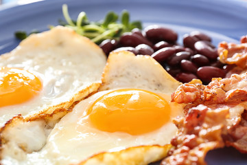 Tasty fried eggs, bacon and beans on plate, closeup