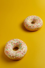 two white donuts on yellow background top view