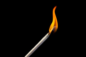 Burning match detail on black background.