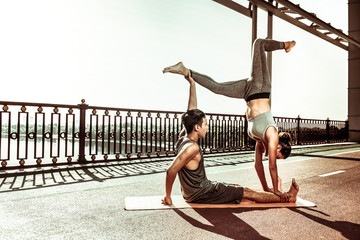 Healthy young couple in sportswear doing acroyoga poses