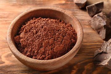 Bowl with cocoa powder on wooden background