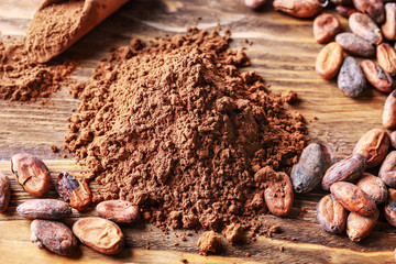 Heap of cocoa powder and beans on wooden background