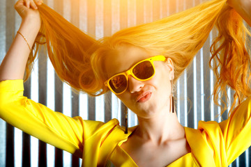 young playful blonde crazy girl in sunglasses with flying hair is grimacing at the camera