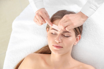 Obraz na płótnie Canvas Young woman undergoing eyebrows epilation in beauty salon