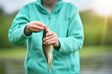 kid boy taking out a hook from the fish