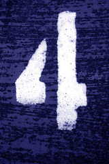 Number 4 in stencil on grungy metal wall in blue tone.