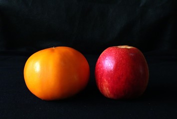 Closeup of Persimmon and apple fruits against black background - tropical still life,Fresh and healthy nutrition.