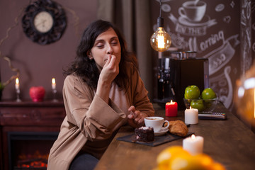 Portrait of cute young woman enjoying a tasty cake in a coffee shop at bar counter