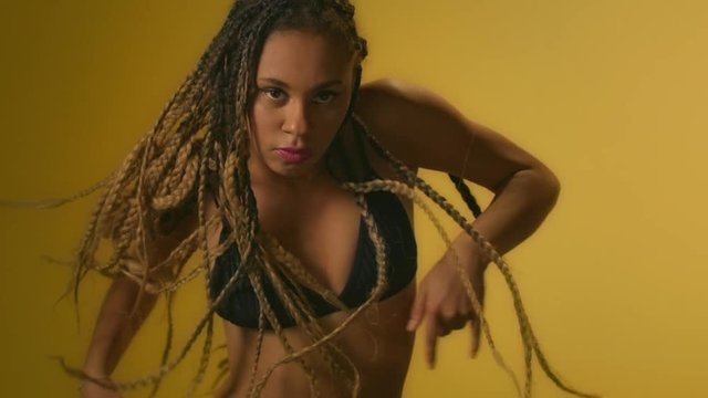 Expressive woman with afro dreadlocks dancing in studio front camera
