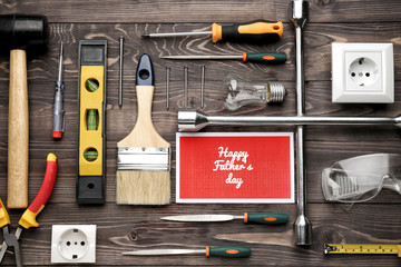 Different tools and card with text "Happy Father's Day" on wooden background
