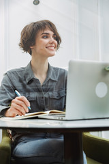 Attractive young woman sitting at the cafe table indoors