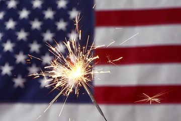 Sparkler against USA flag. Independence Day celebration - obrazy, fototapety, plakaty