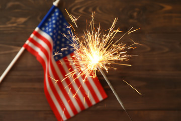 Sparkler and USA flag on wooden background. Independence Day celebration