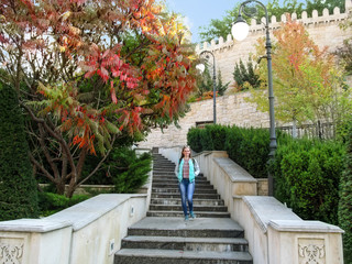 Slender blonde girl descends the stairs against of a copy of the wall of Baku fortress and oriental...