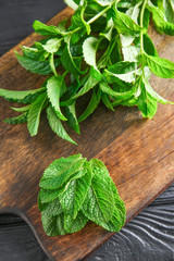 Board with green mint on wooden background