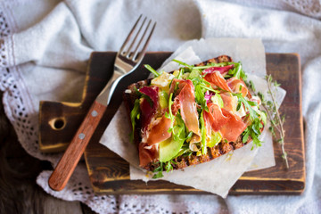 Toast with prosciutto, arugula, cheese and avocado. Appetizer