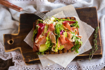 Toast with prosciutto, arugula, cheese and avocado. Appetizer