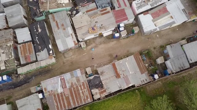 An overhead aerial shot of people and a dog walking through the streets of a shanty town, informal settlement in Africa.