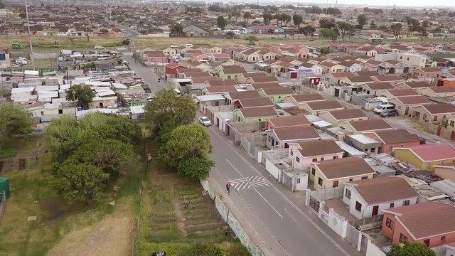 Aerial shot of low income, low-cost (RDP) housing across the road from a tin shack informal settlement in a South African township.