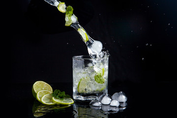 Summer cocktail mojito with splash on black background..